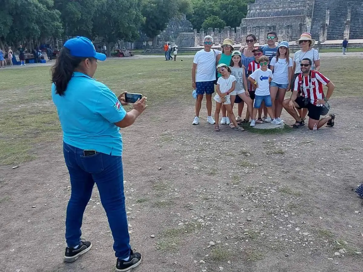 Guia tomando fotos de visitantes enfrente del templo de las 100 columnas
